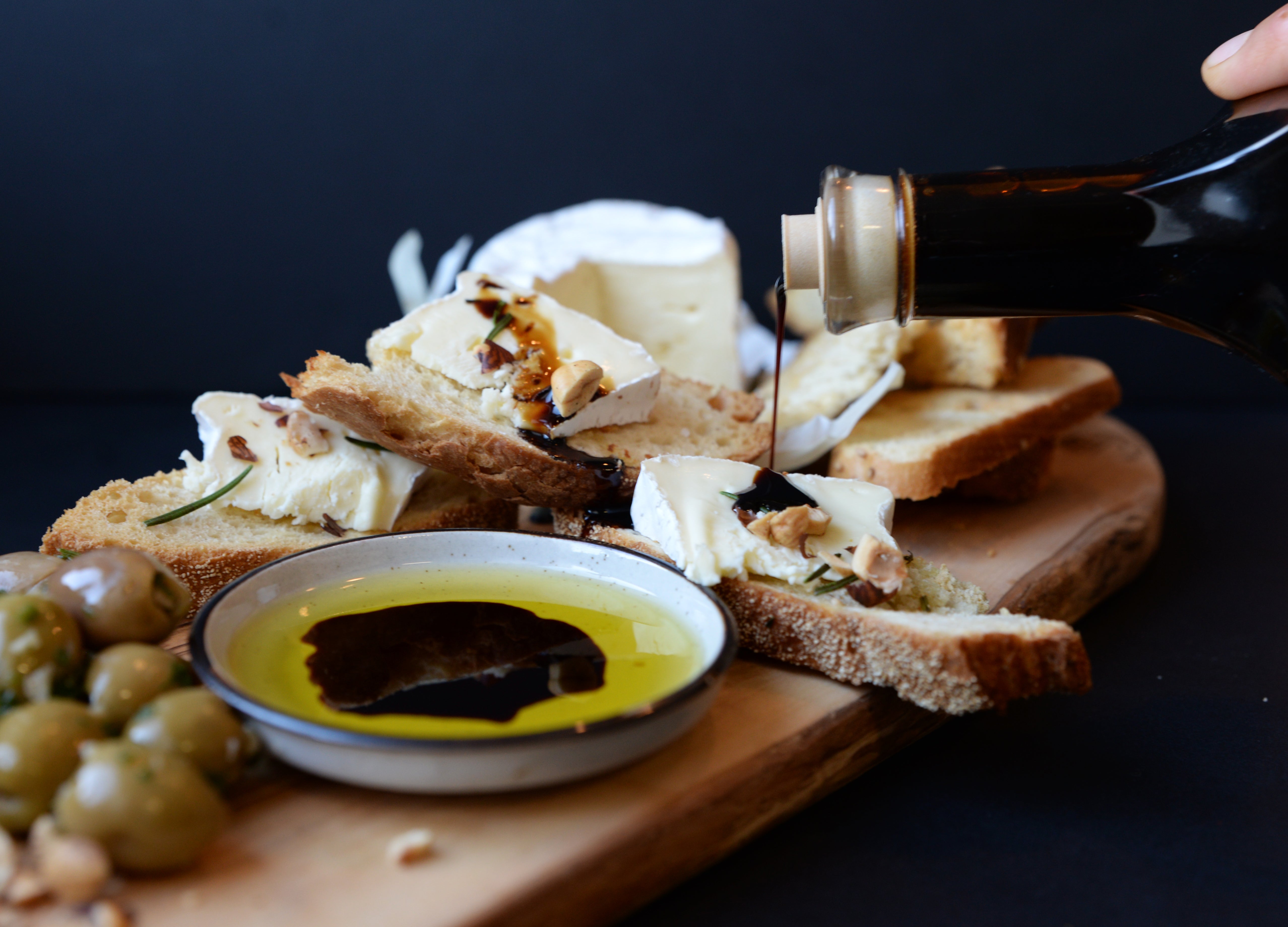 Cutting board with sliced baguette and a dipping bowl of balsamic vinegar and oil — showcasing the elegance of aged balsamic.